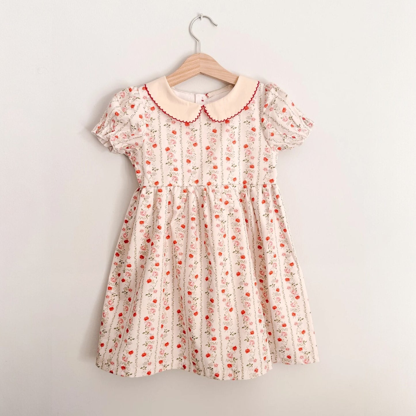 Floral dress on a hanger against a plain background