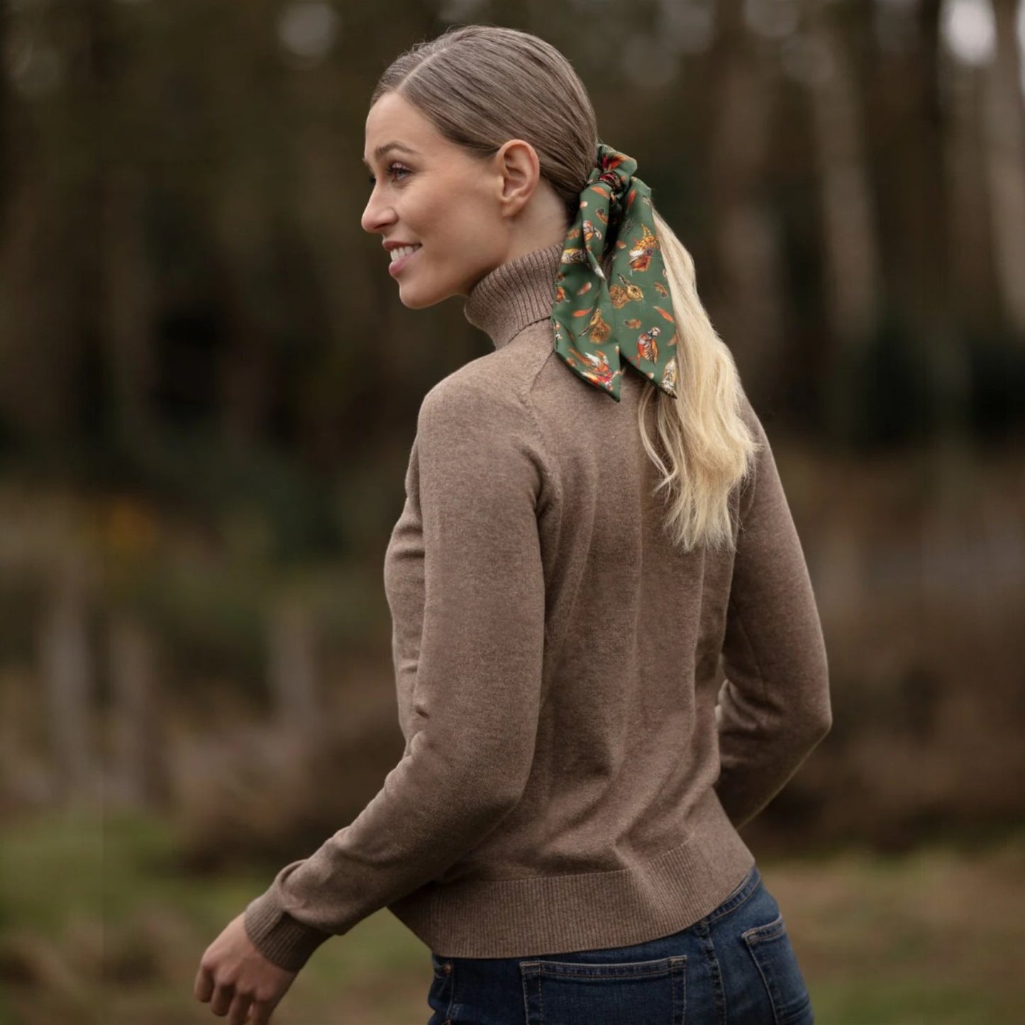Woman wearing a brown sweater with a patterned hair scarf outdoors