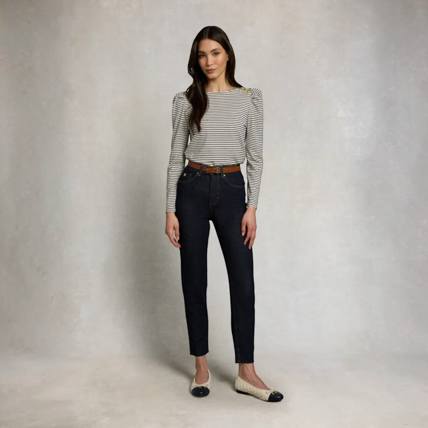 Woman wearing a striped top and black jeans against a plain background