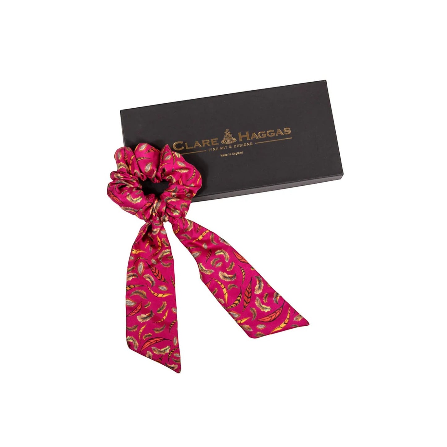 Pink patterned scrunchie with a black box featuring 'Clare Haggas' branding on a white background.
