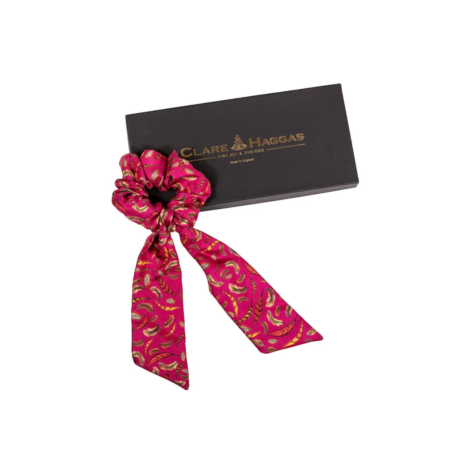 Pink patterned scrunchie with a black box featuring 'Clare Haggas' branding on a white background.
