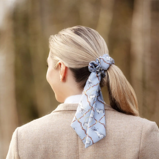 Person with a blue patterned scrunchie in their hair, standing in a forest.