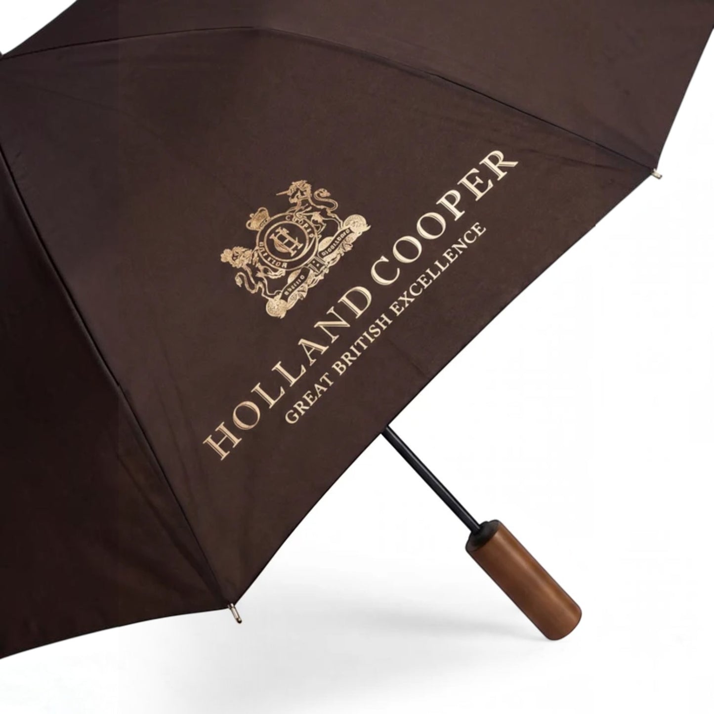 A dark brown umbrella with a wooden handle, featuring a gold printed crest and the text 'HOLLAND COOPER GREAT BRITISH EXCELLENCE' on the canopy, set against a plain white background.