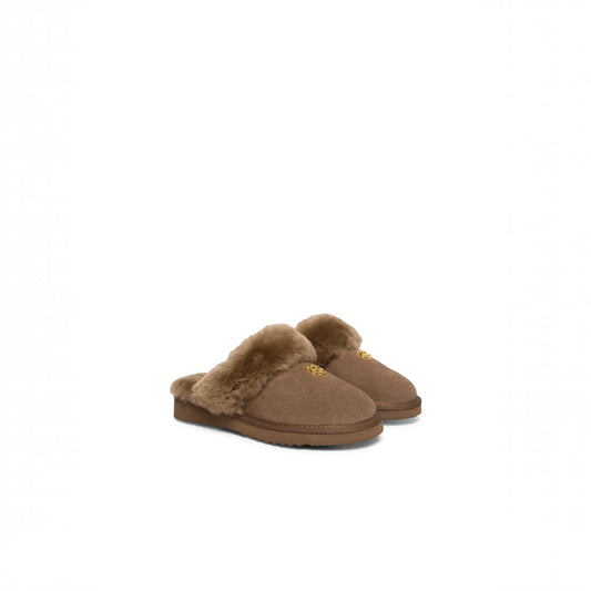 A pair of brown suede slip-on slippers with fluffy tan shearling lining and a small gold logo on the side, set against a plain white background.