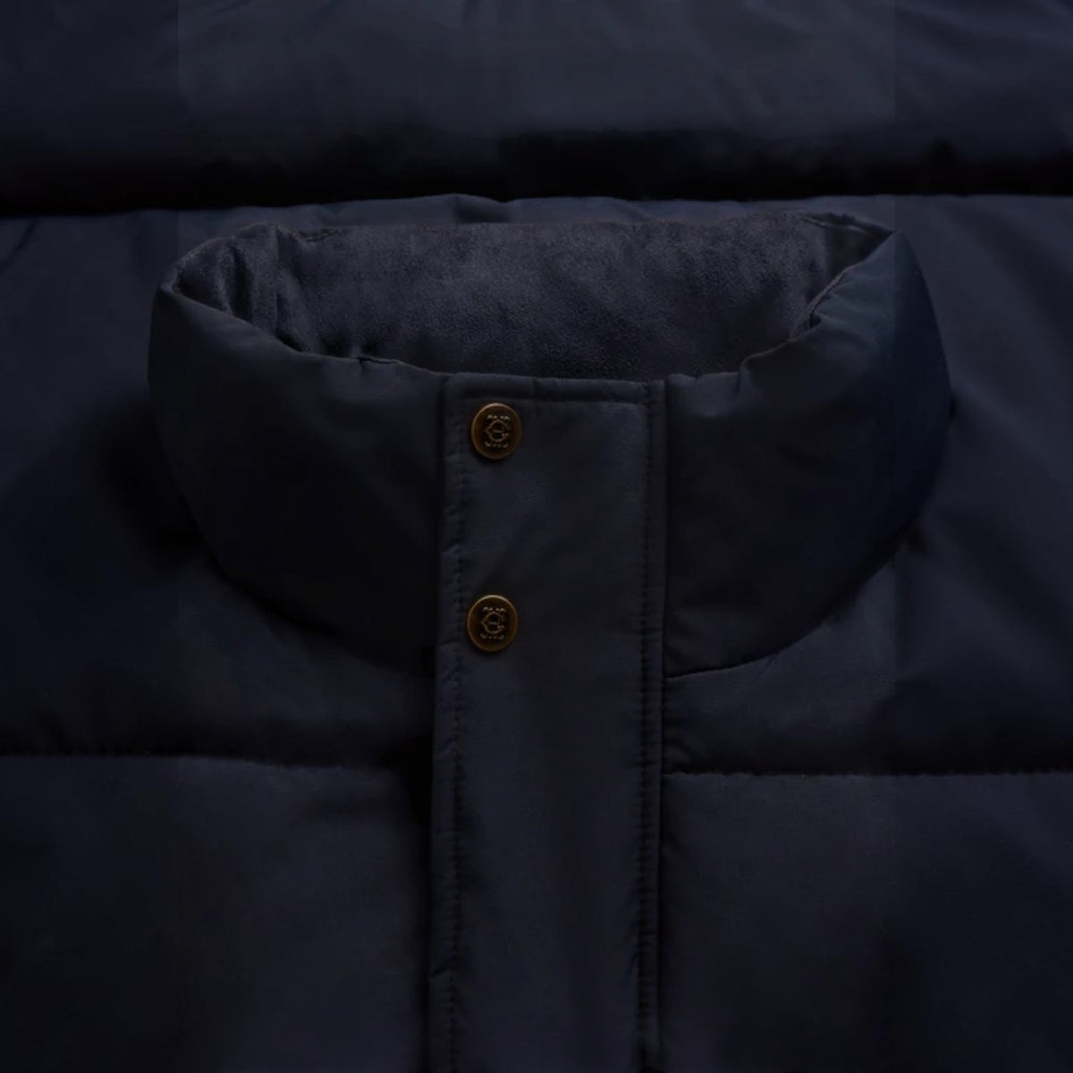 Close-up of a dark navy puffer jacket showing the collar, button closure, and quilted fabric texture.