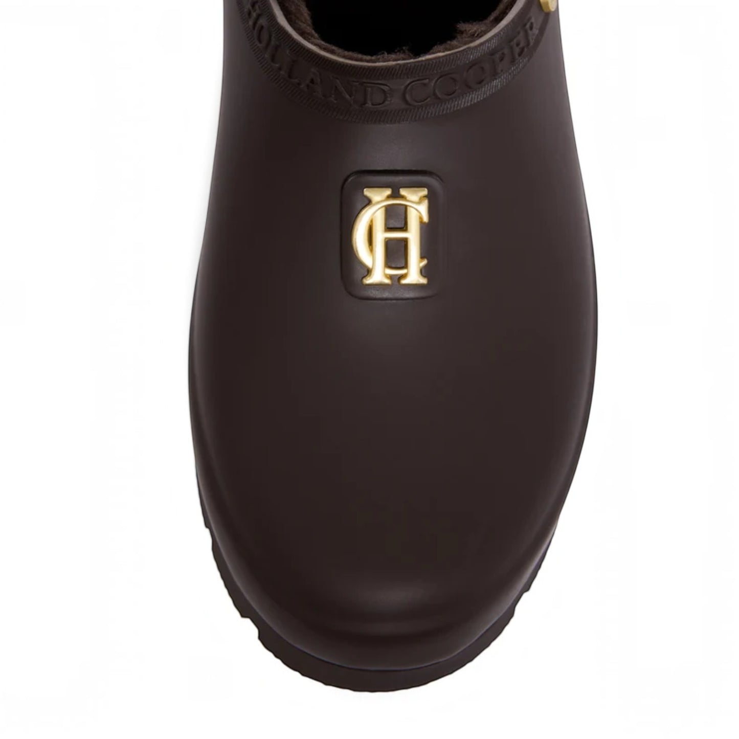 A close-up top-down view of a dark brown rubber rain boot with a gold 'HC' logo emblem on the side and 'HOLLAND COOPER' embossed on the collar, set against a plain white background.