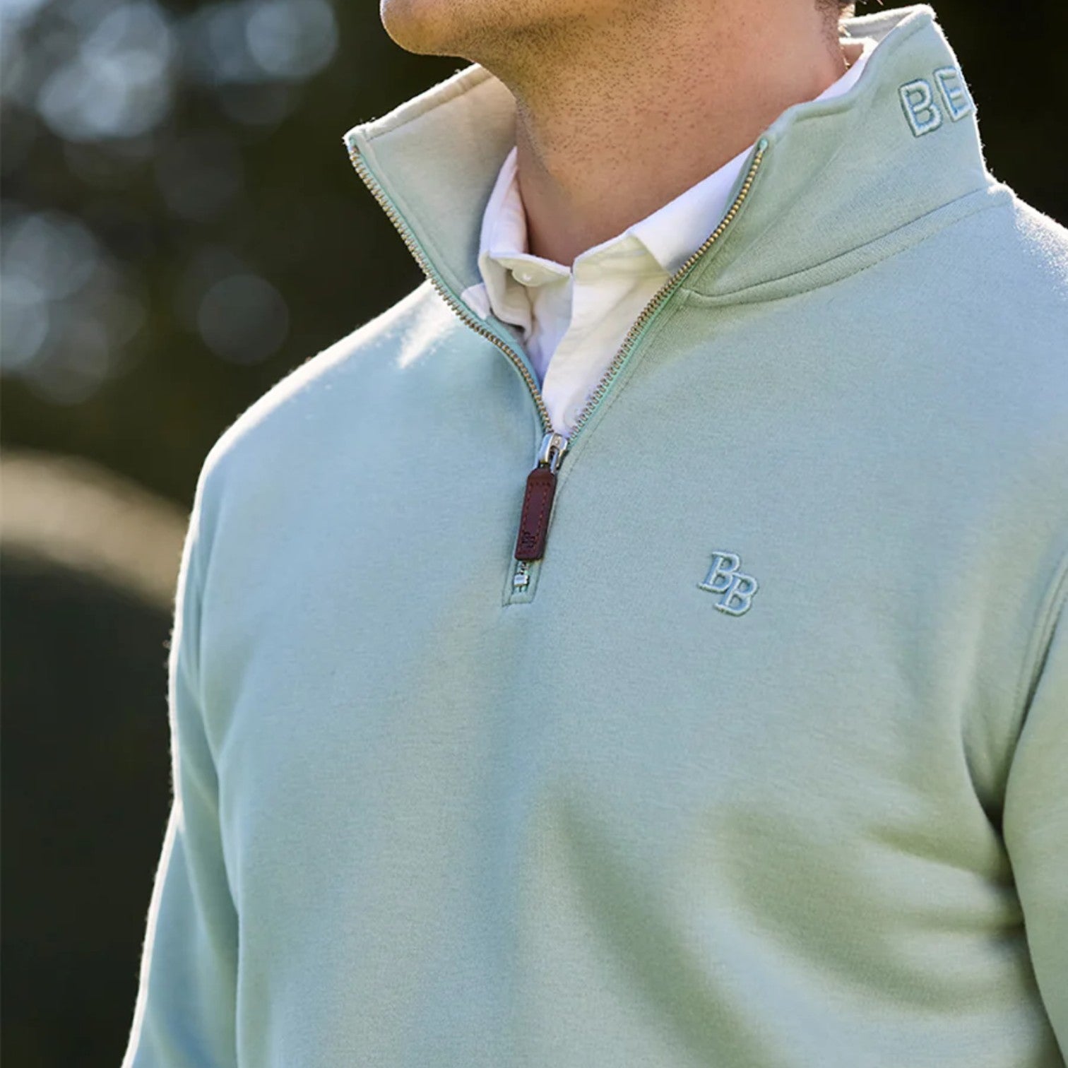 Light blue pullover with a brand logo worn by a person, blurred background