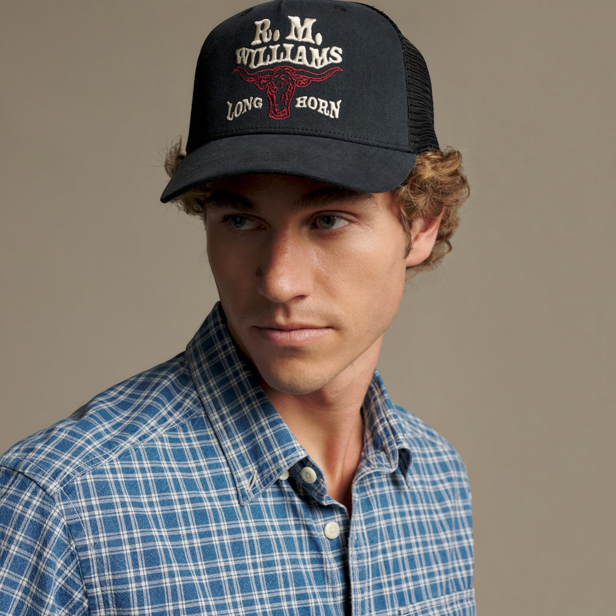 A man wearing a black trucker hat with 'R.M.