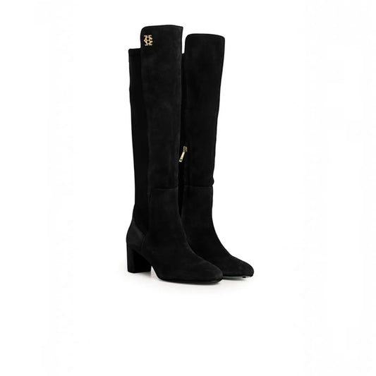 A pair of black suede over-the-knee boots with a block heel and a small gold logo on the top collar, shown against a plain white background.