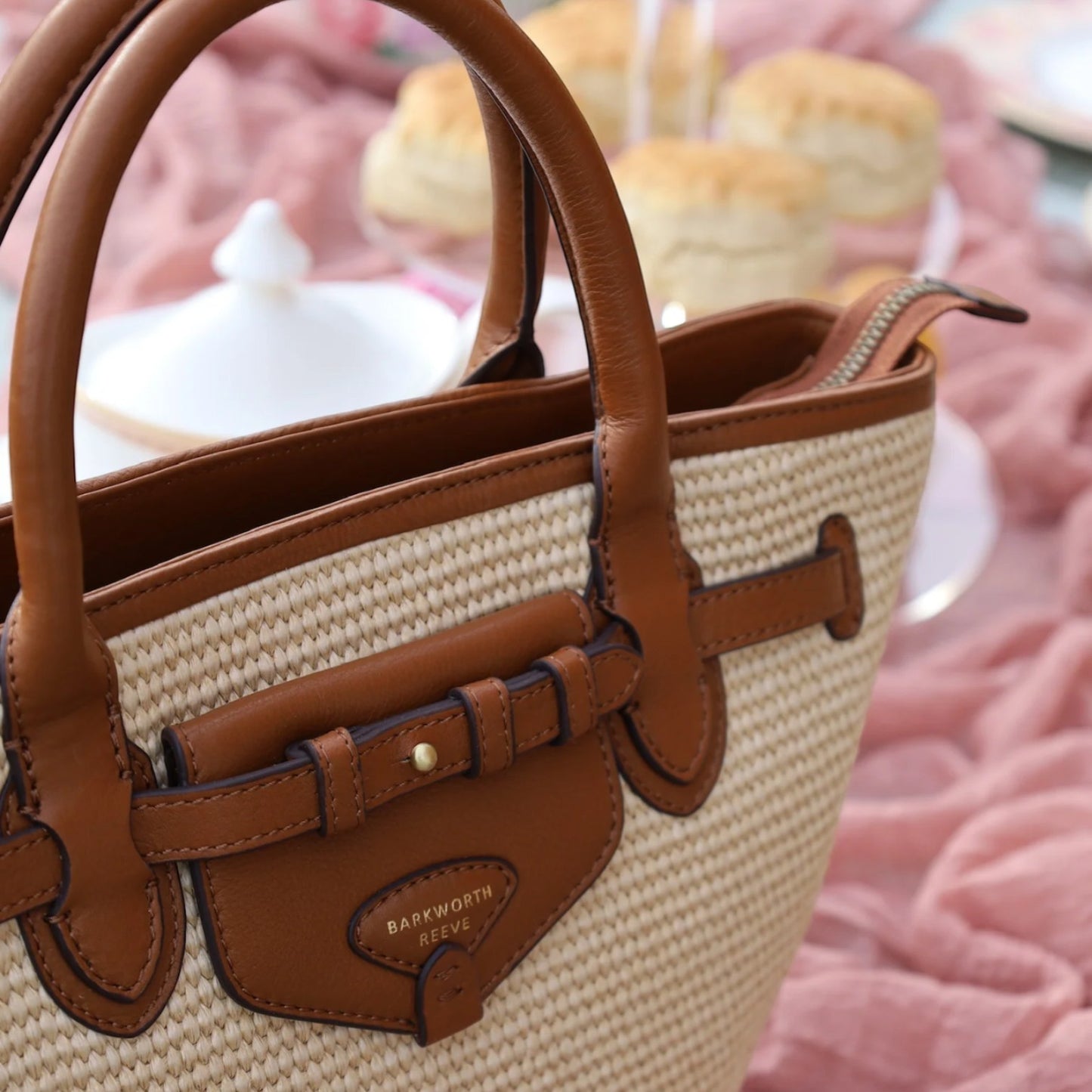 Brown and beige handbag with leather accents on a blurred background