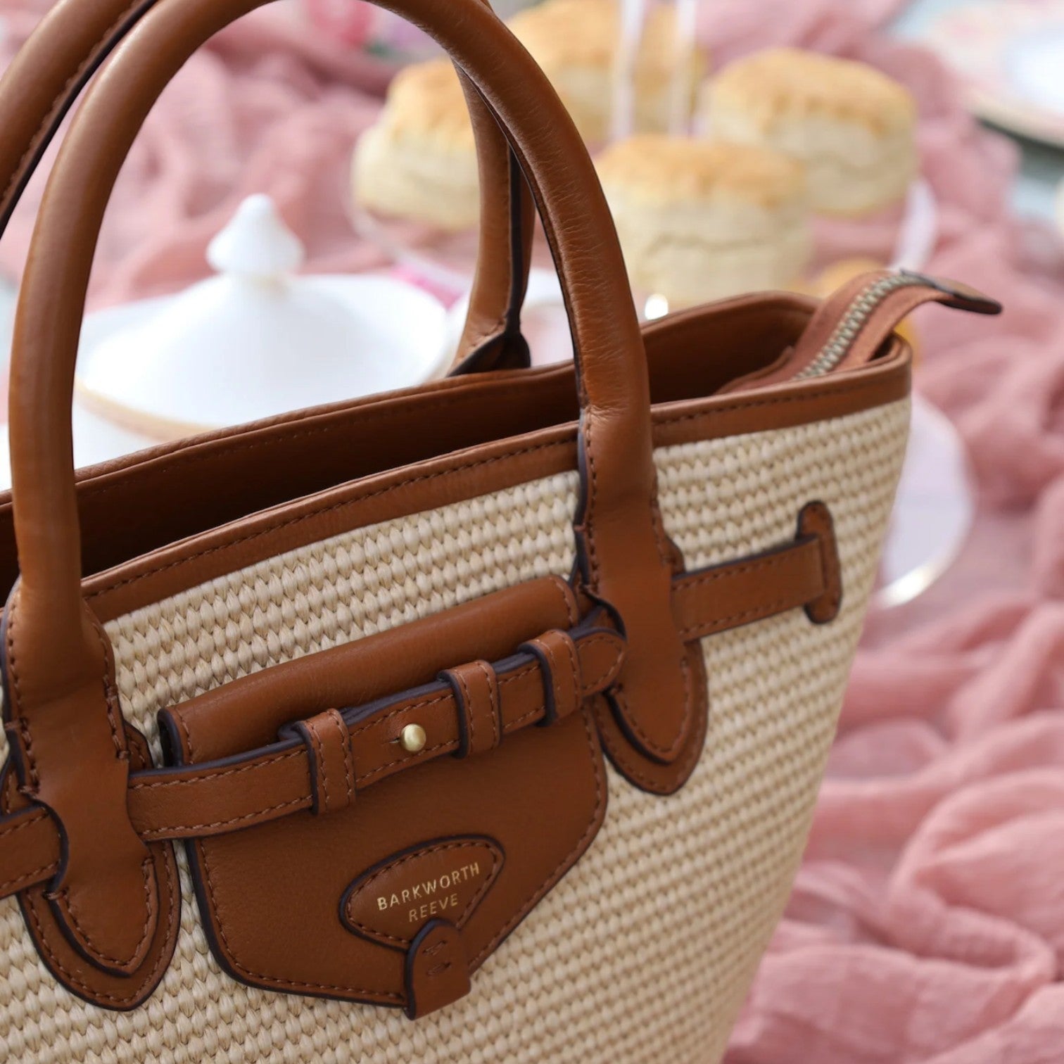 Brown and beige handbag with leather accents on a blurred background