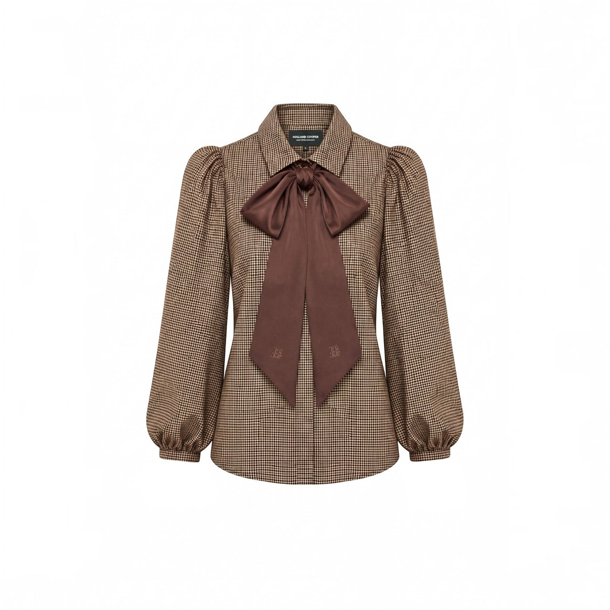 A brown and beige houndstooth blouse with a large dark brown satin bow at the collar, featuring puffed long sleeves and a button-down front.