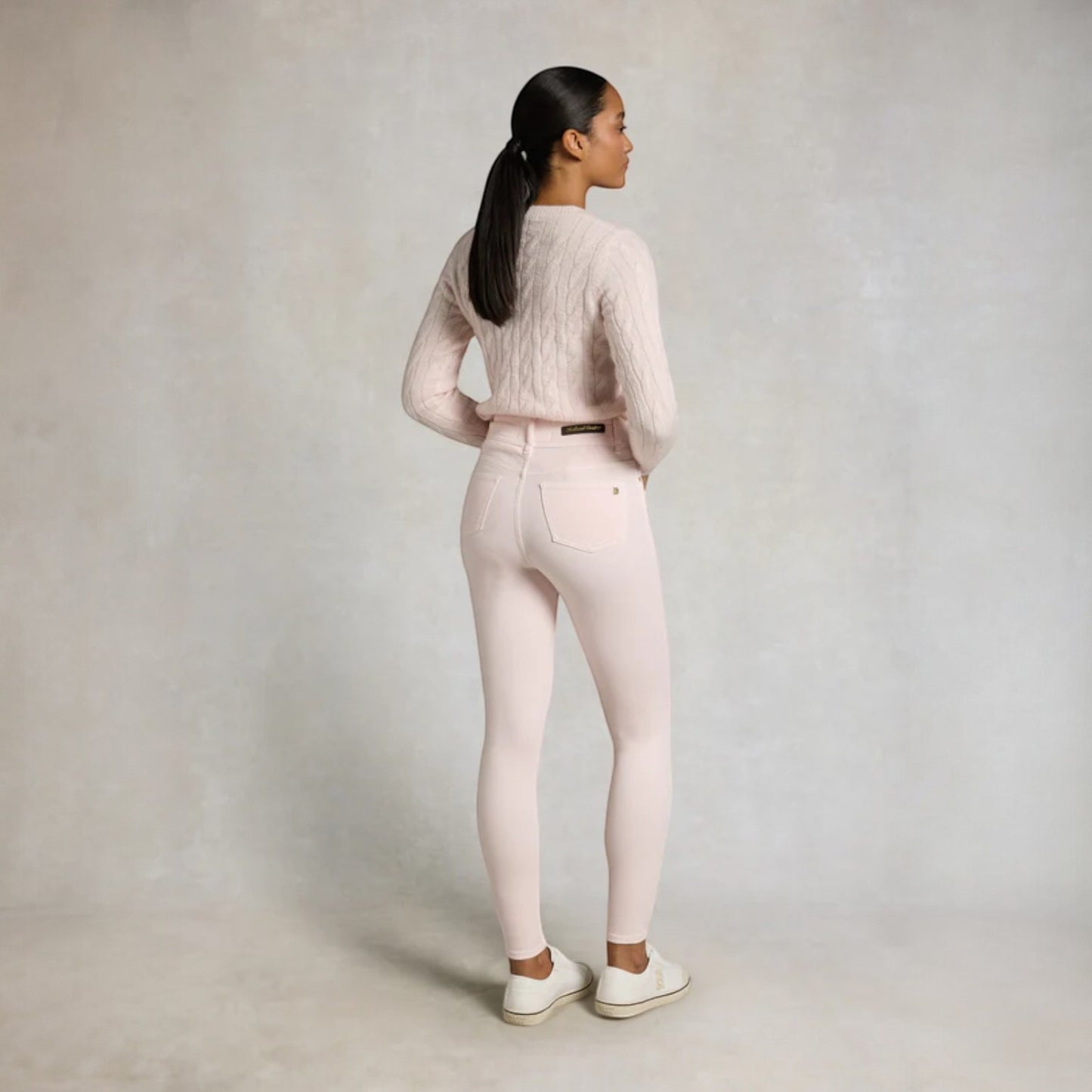 Woman wearing a light pink outfit with a plain background