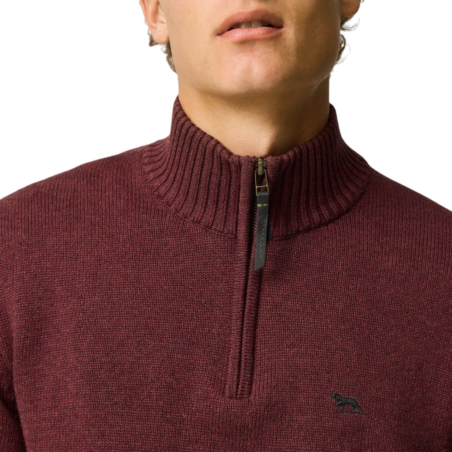 Close-up of a person wearing a maroon sweater with a quarter zip and a brand logo.