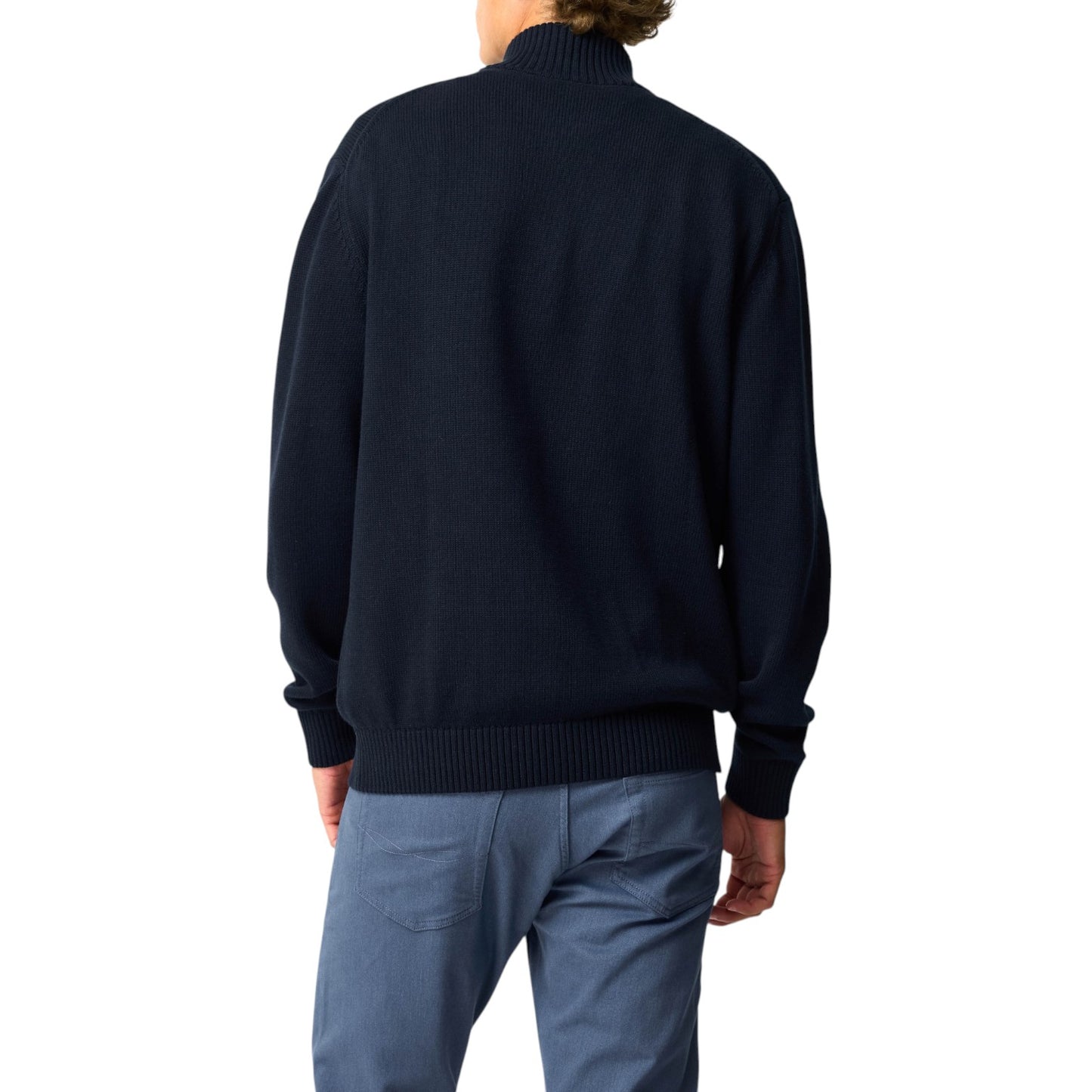 Person wearing a navy sweater and light blue pants on a white background