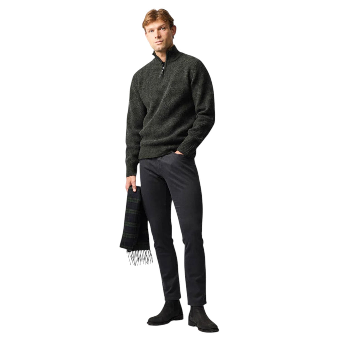 Man wearing a dark green sweater, black pants, and holding a black scarf on a white background