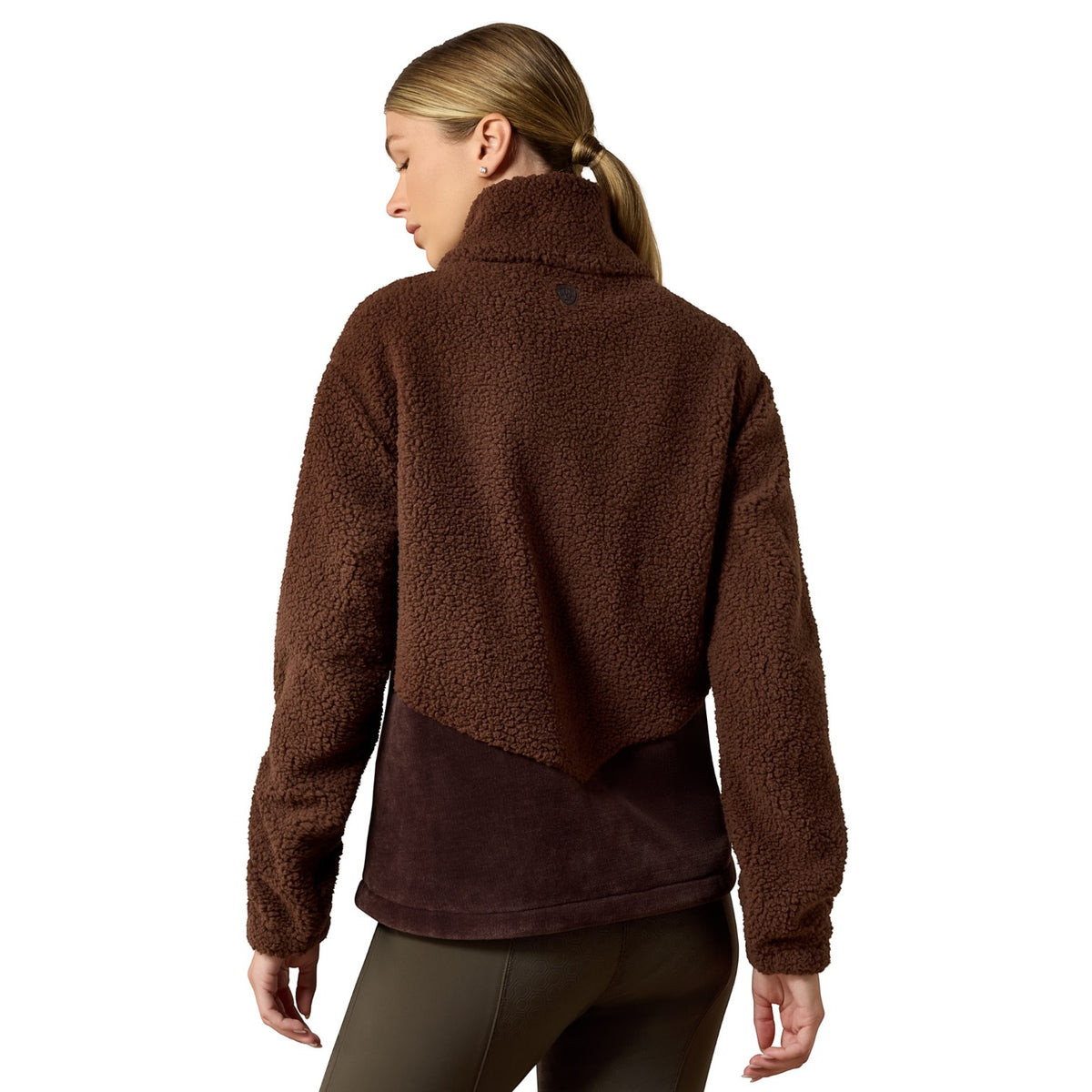 A woman shown from the back wearing a brown sherpa fleece cropped jacket with a darker brown panel at the bottom, paired with dark olive leggings, against a plain white background.
