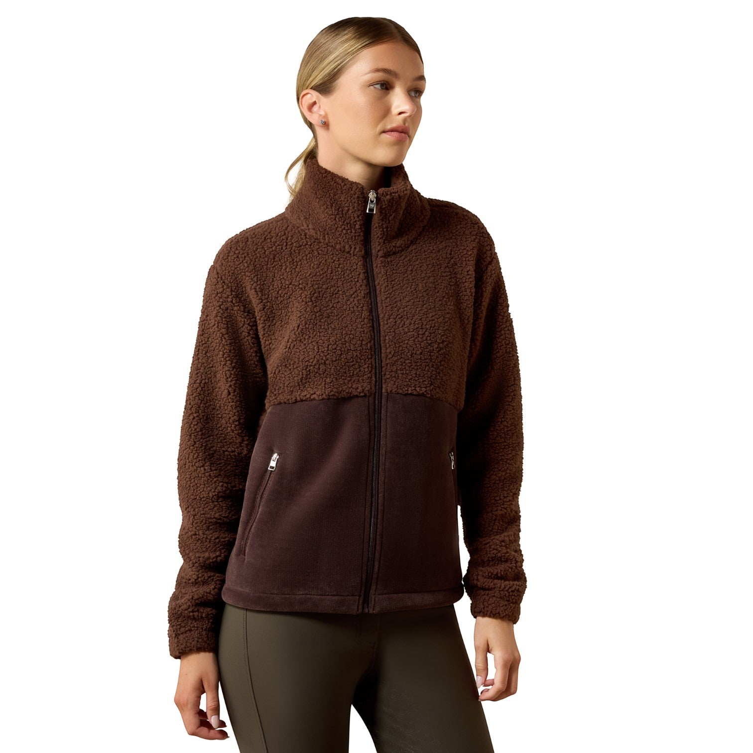 A woman wearing a brown fleece jacket with a darker brown lower panel, standing against a plain white background.