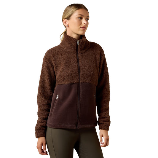 A woman wearing a brown fleece jacket with a darker brown lower panel, standing against a plain white background.