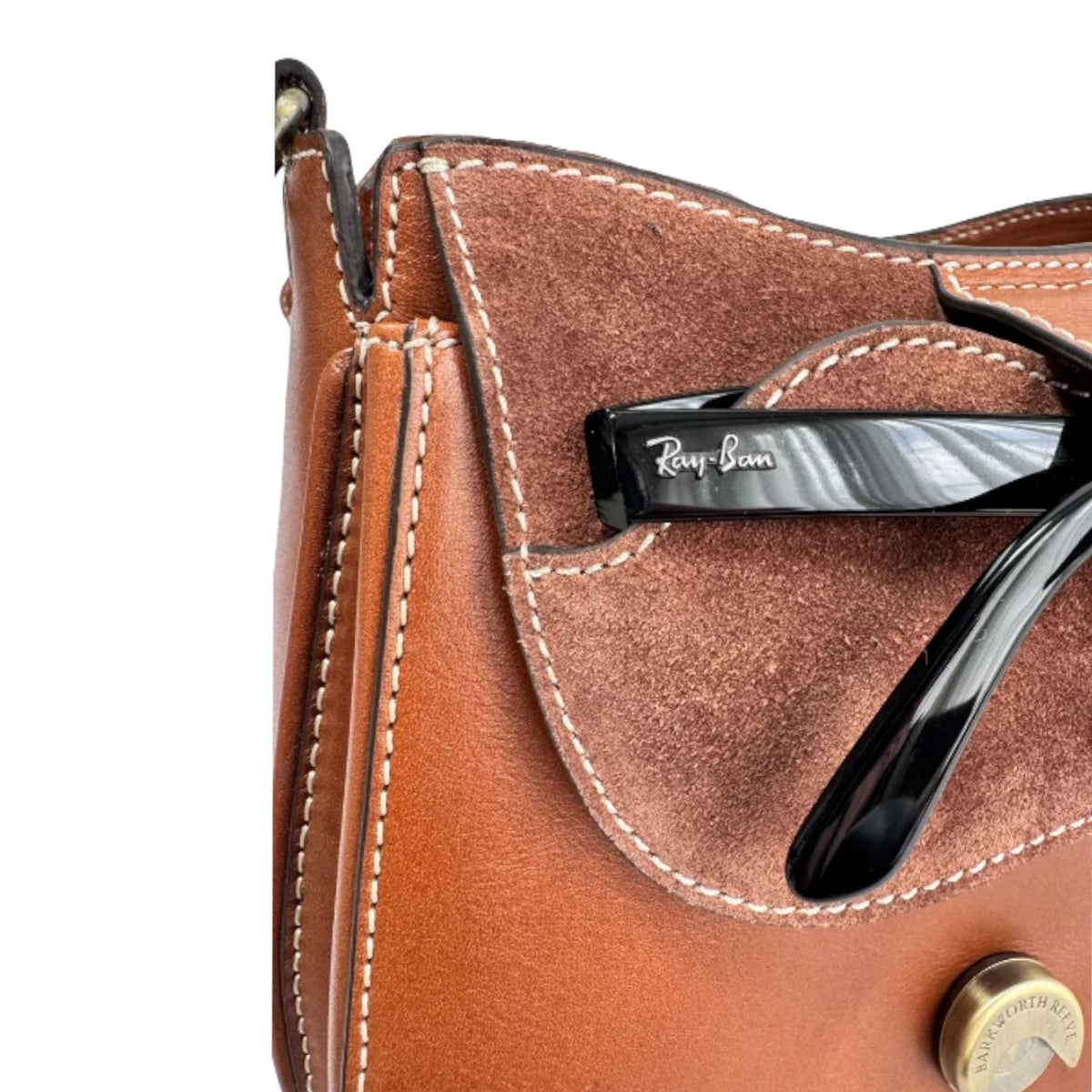 Close-up of a brown leather and suede handbag with black Ray-Ban sunglasses resting in a side pocket, on a white background.