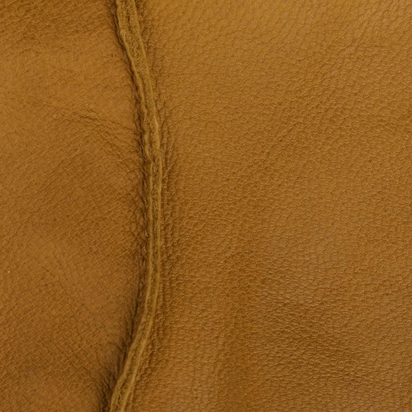 A close-up of textured tan leather with a visible center seam running vertically.
