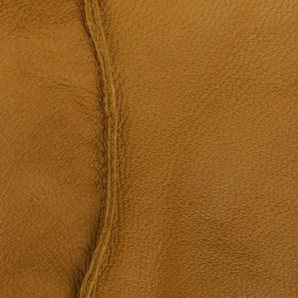A close-up of textured tan leather with a visible center seam running vertically.