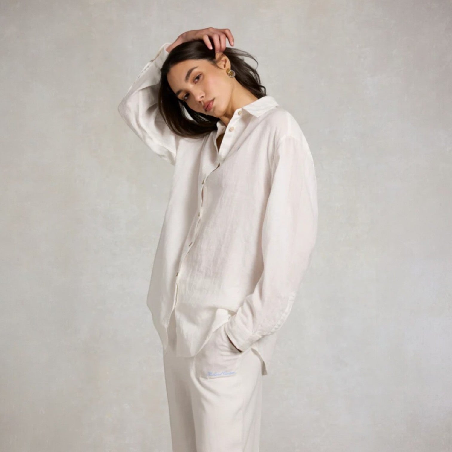 Person wearing a white shirt and pants against a plain background