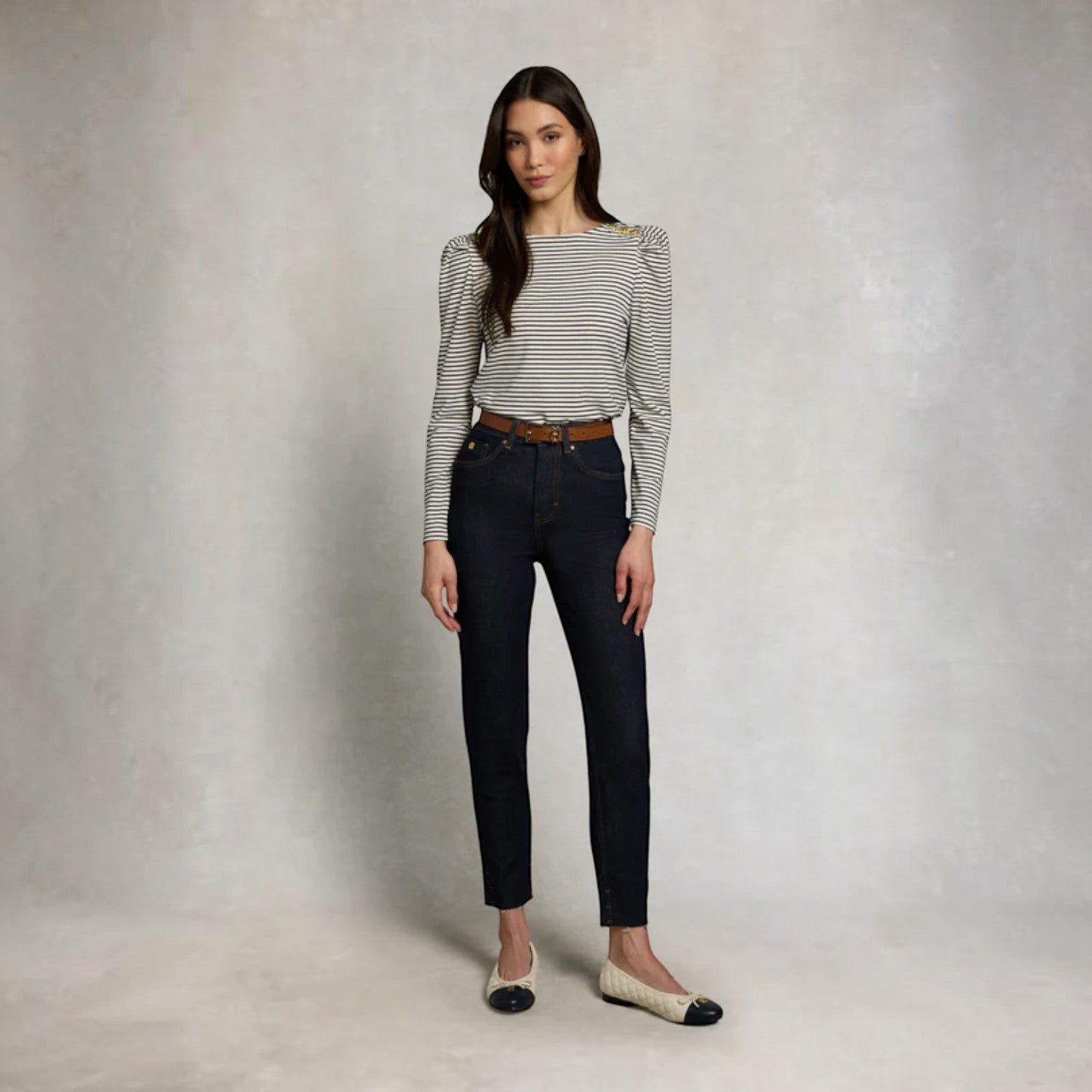 Woman wearing a striped top and black jeans against a plain background
