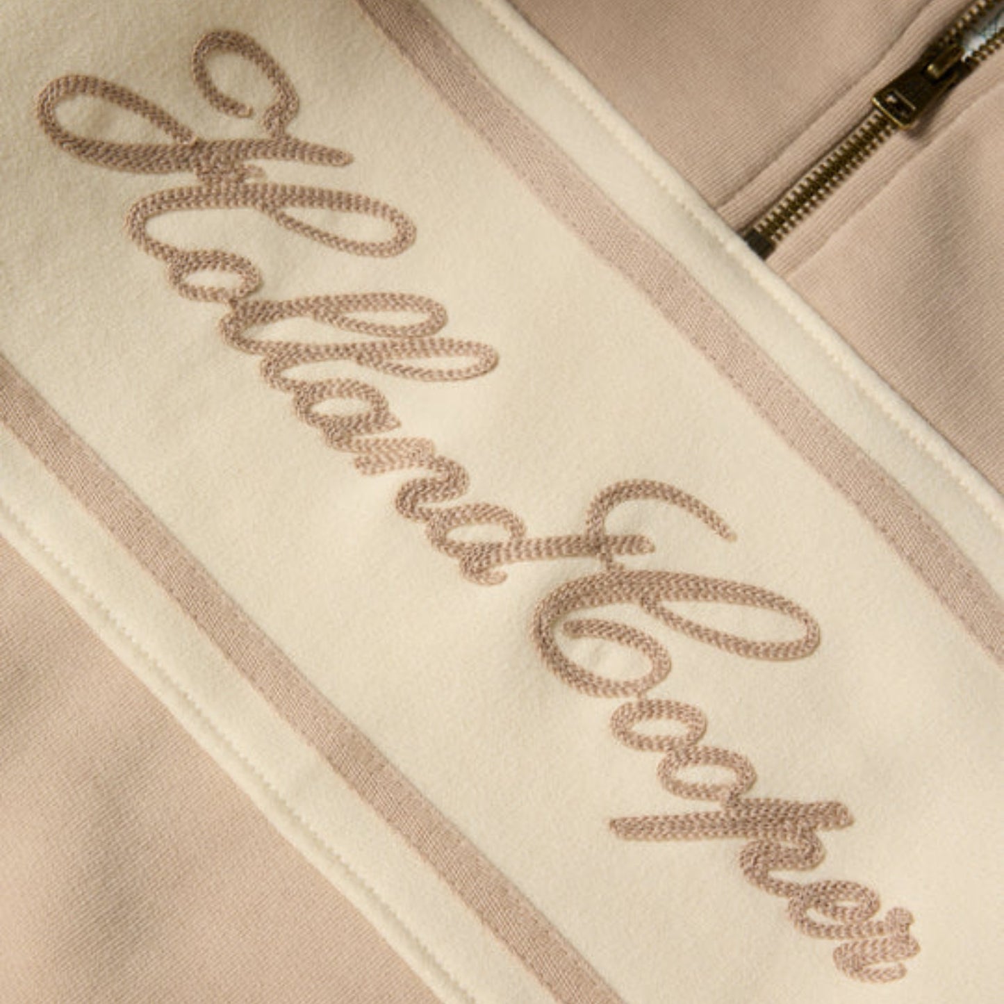 Close-up of a beige jacket with 'Allan Clarke' embroidered on it.
