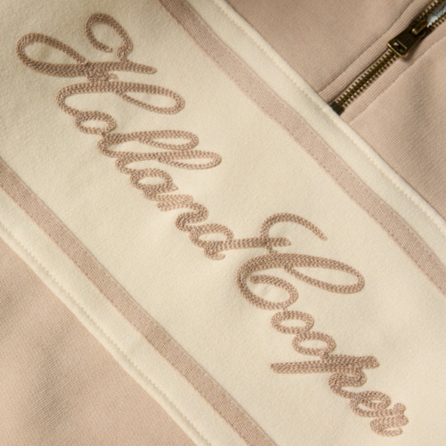 Close-up of a beige jacket with 'Allan Clarke' embroidered on it.