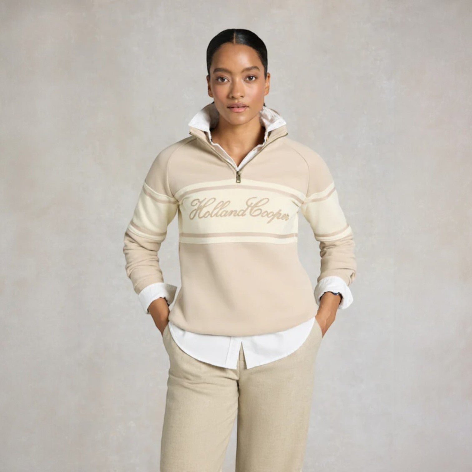 Woman wearing a beige Holland Cooper sweater and pants on a plain background