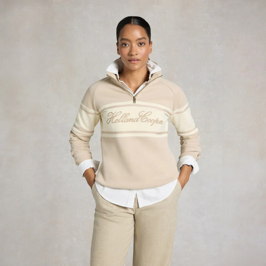 Woman wearing a beige Holland Cooper sweater and pants on a plain background