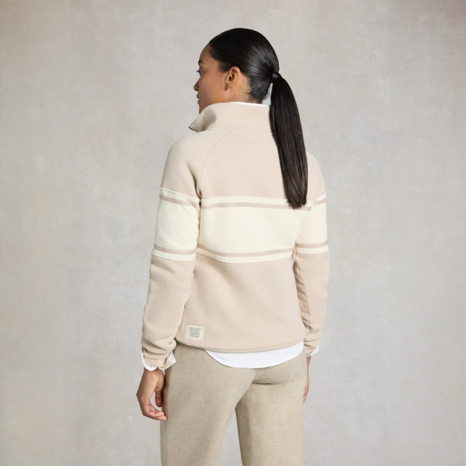Woman wearing a beige and white striped fleece jacket against a plain background