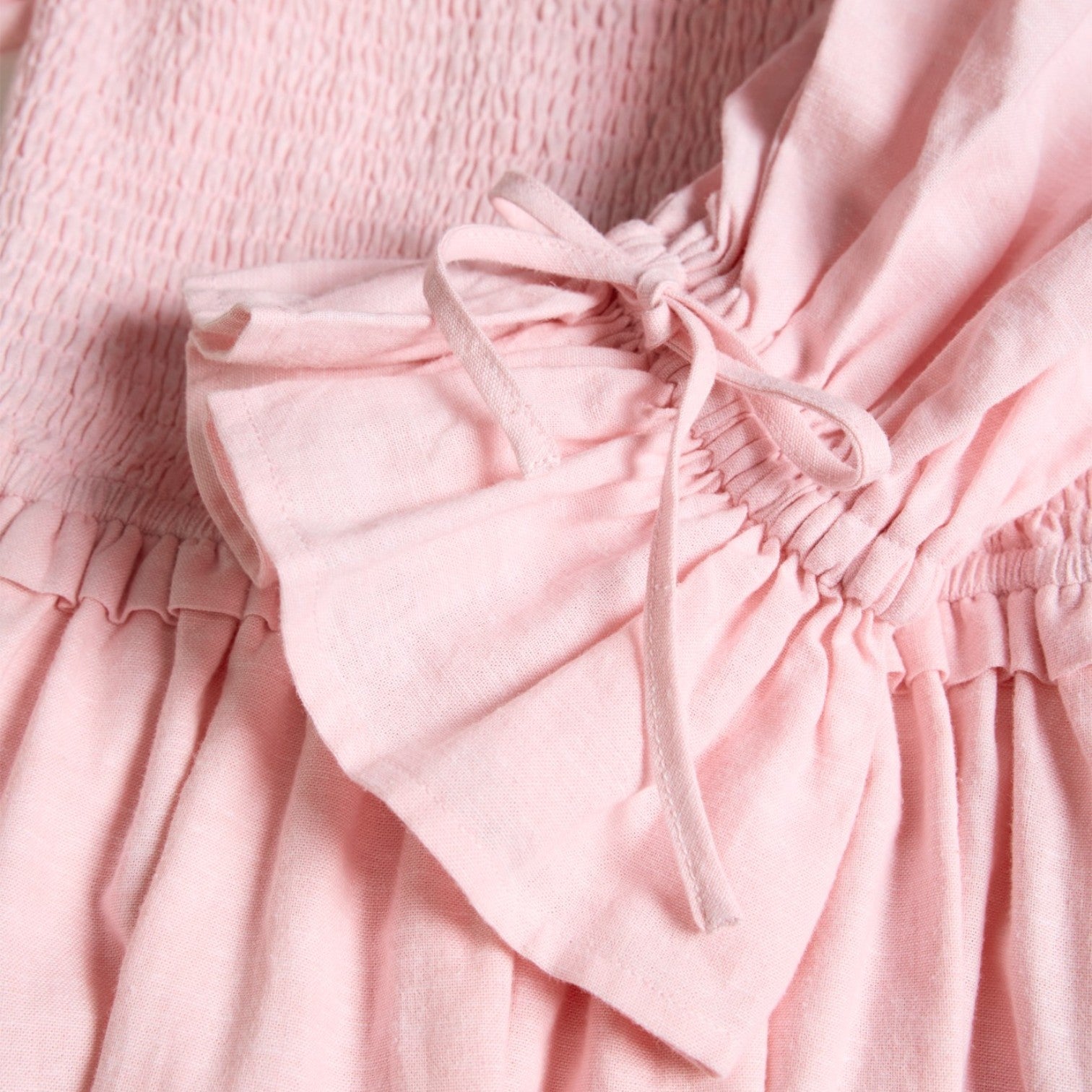Close-up of a pink dress with a bow detail