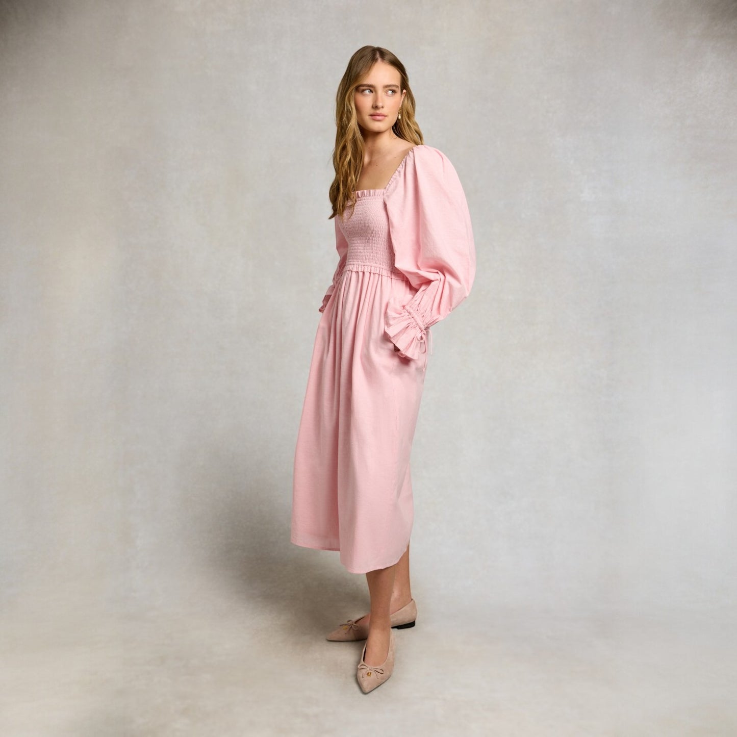 Woman wearing a pink dress with a plain background