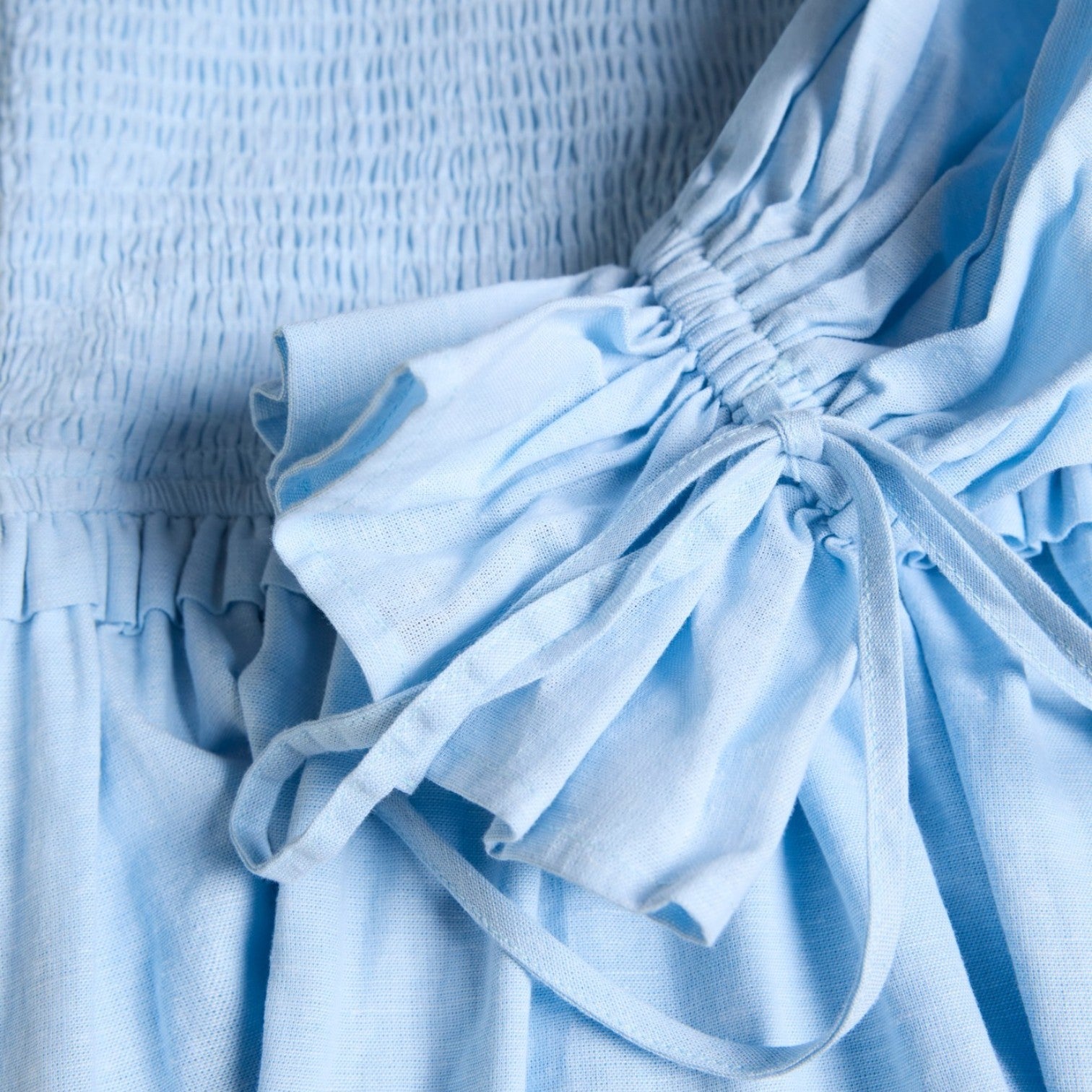 Close-up of a light blue dress with a bow detail.