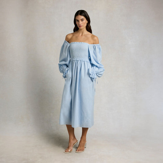 Woman wearing a light blue off-shoulder dress against a plain background