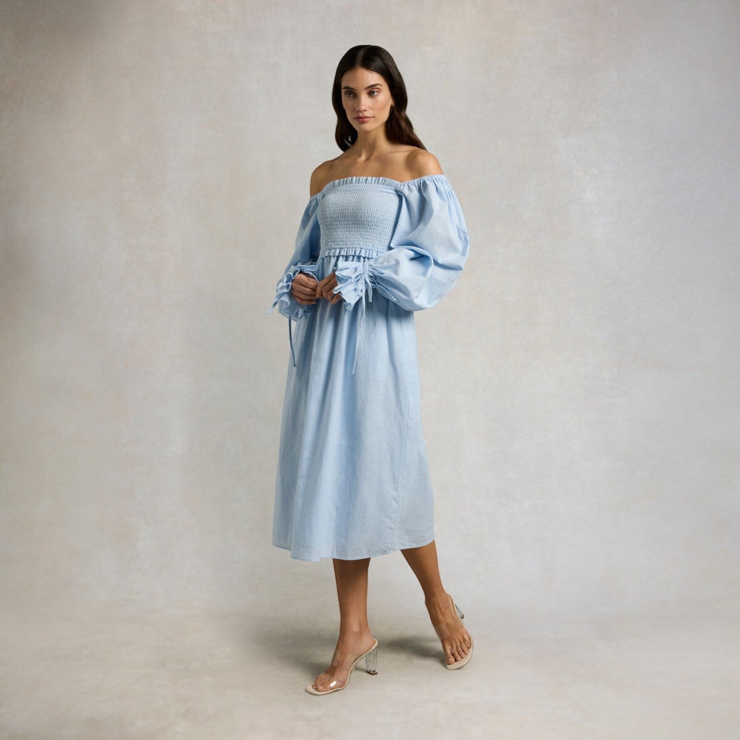 Woman wearing a light blue off-shoulder dress against a plain background