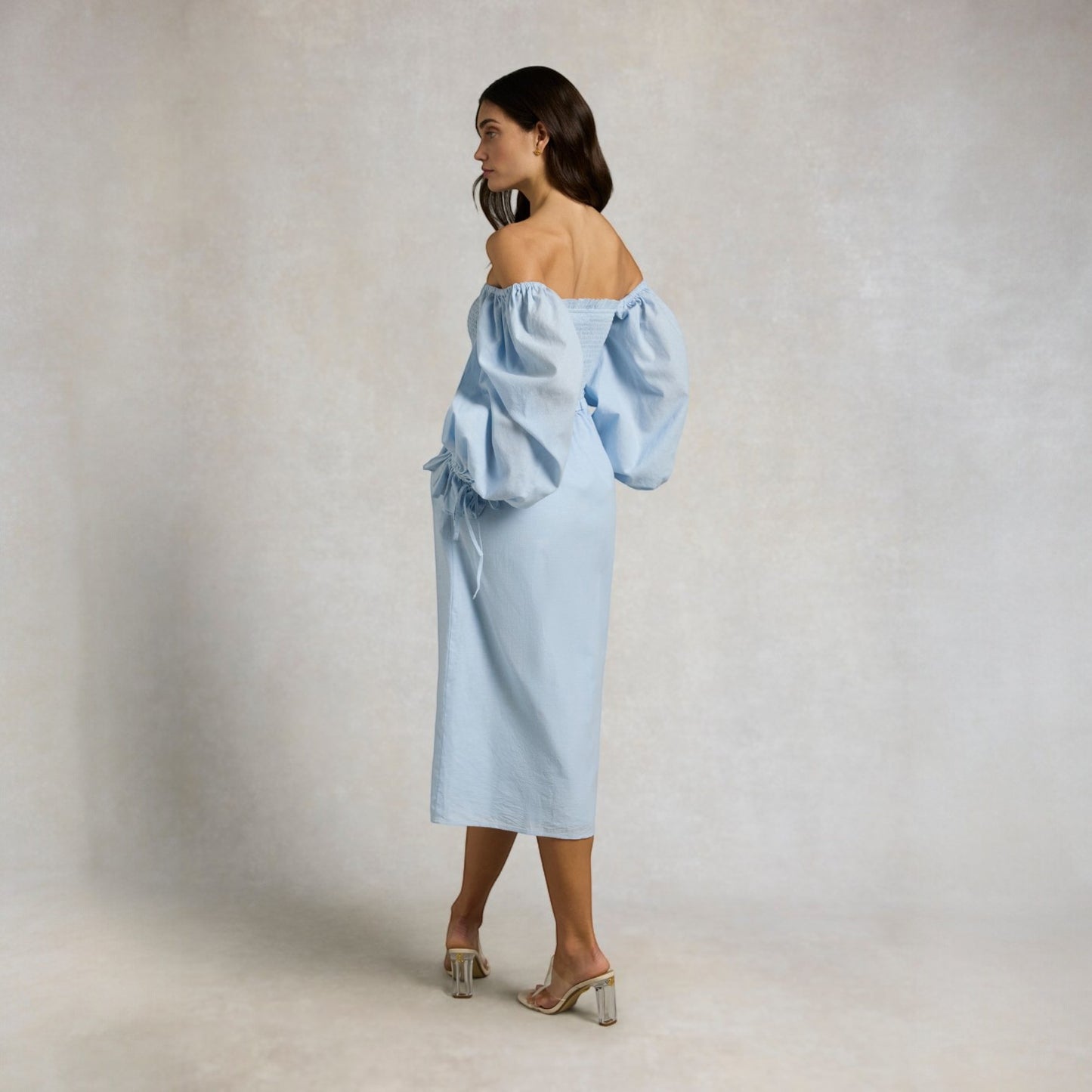 Woman wearing a light blue off-shoulder top and skirt set against a plain background