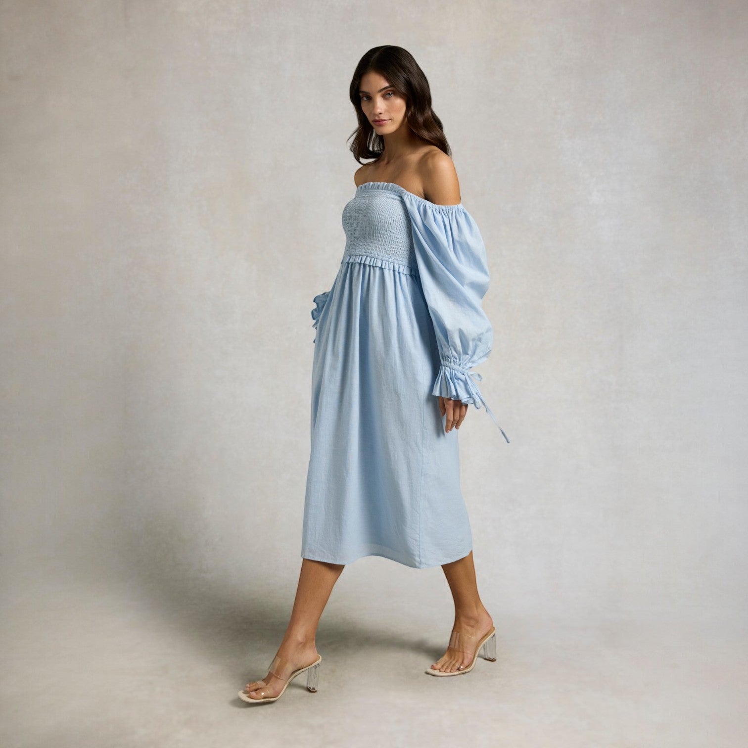 Woman wearing a light blue off-shoulder dress against a plain background
