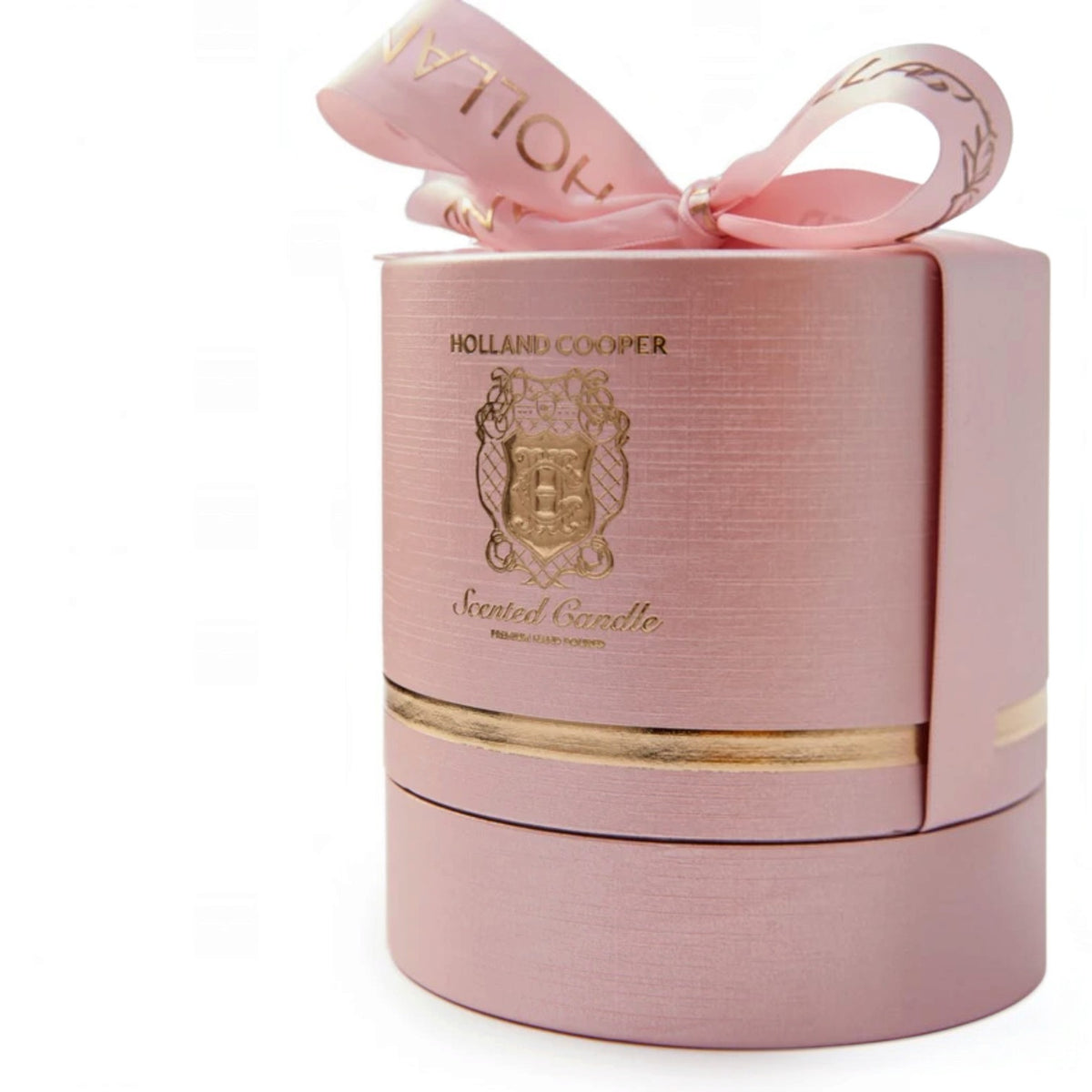 A pink cylindrical gift box with a matching pink ribbon bow, featuring gold foil branding for Holland Cooper Scented Candle on a clean white background.