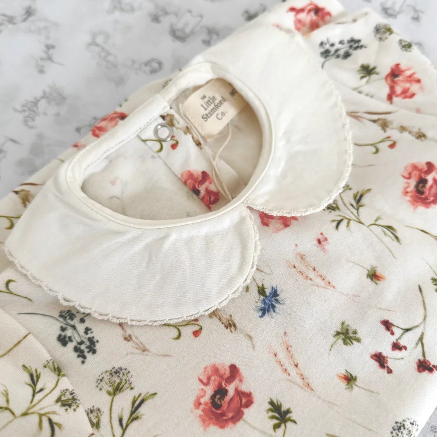 Floral-patterned fabric with a white collar on a textured surface