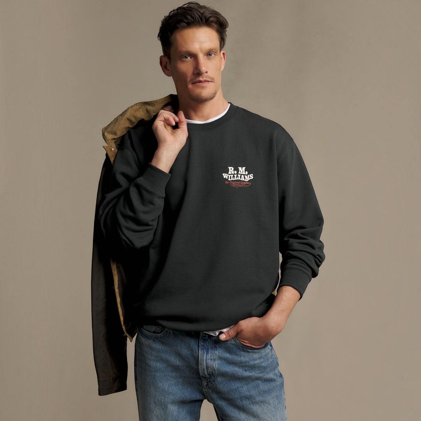 A man wearing a black crewneck sweatshirt with a white 'B.N.
