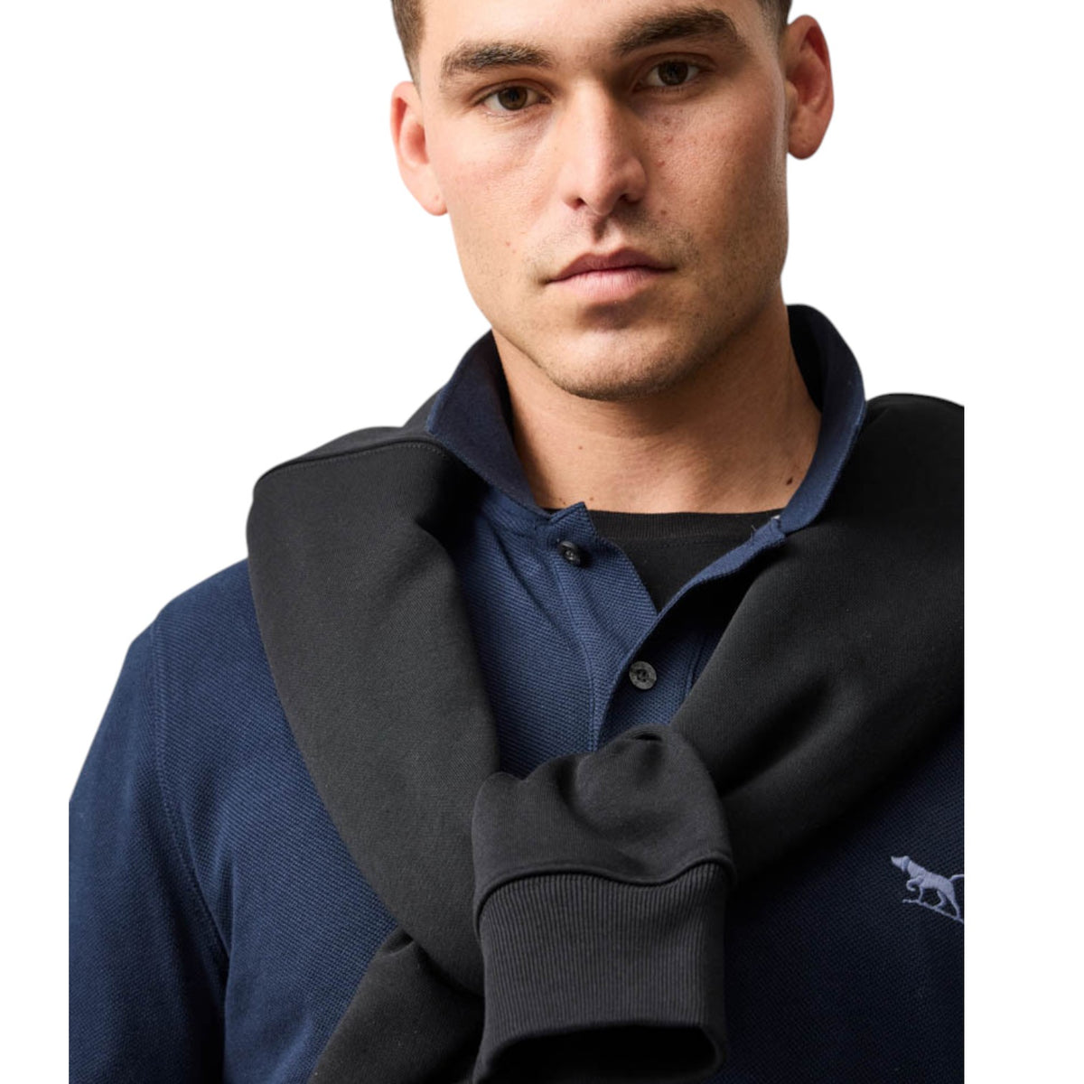 Man wearing a navy sweater with a dark gray hood over his shoulders on a white background