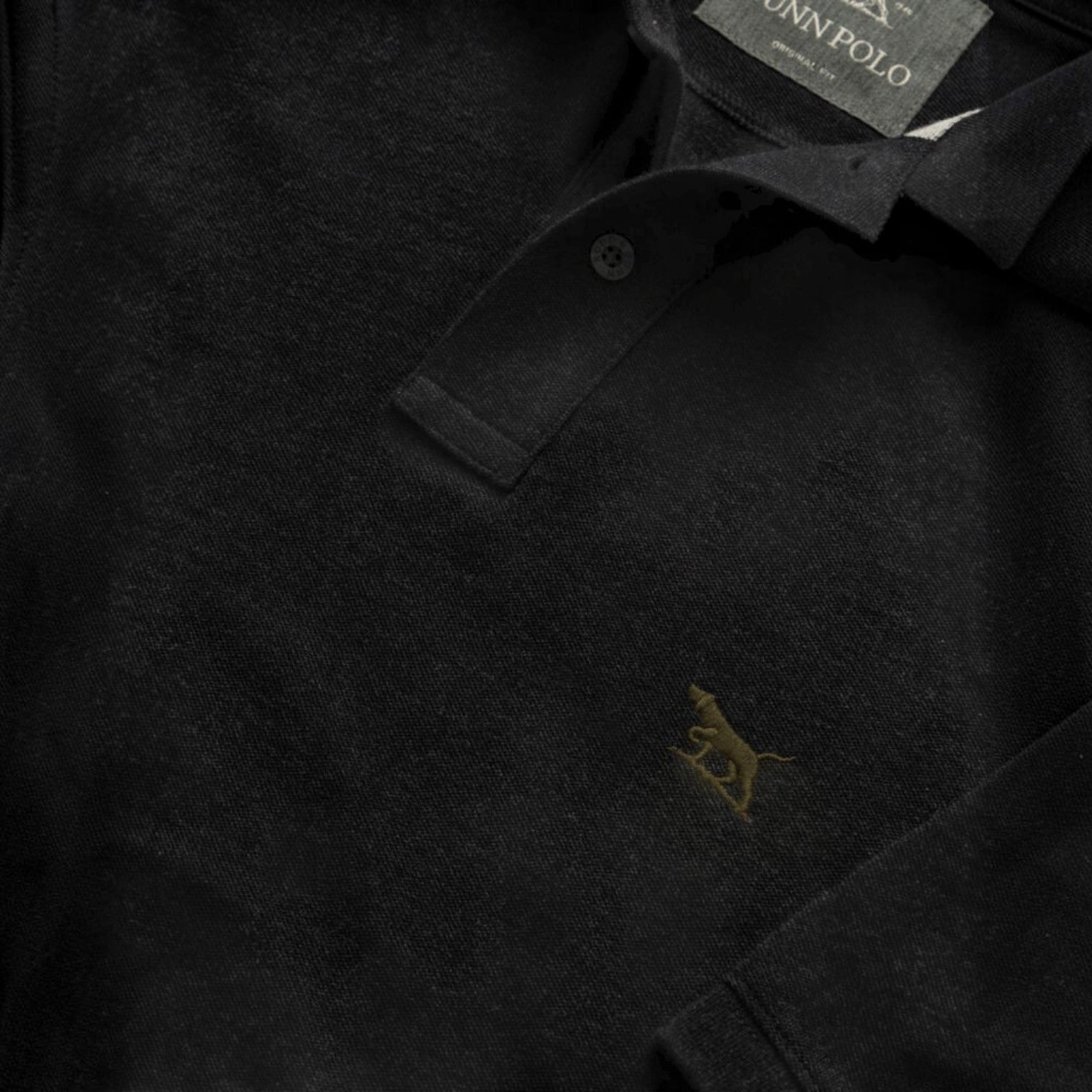 Close-up of a black polo shirt with a logo and tag, suitable for casual wear.