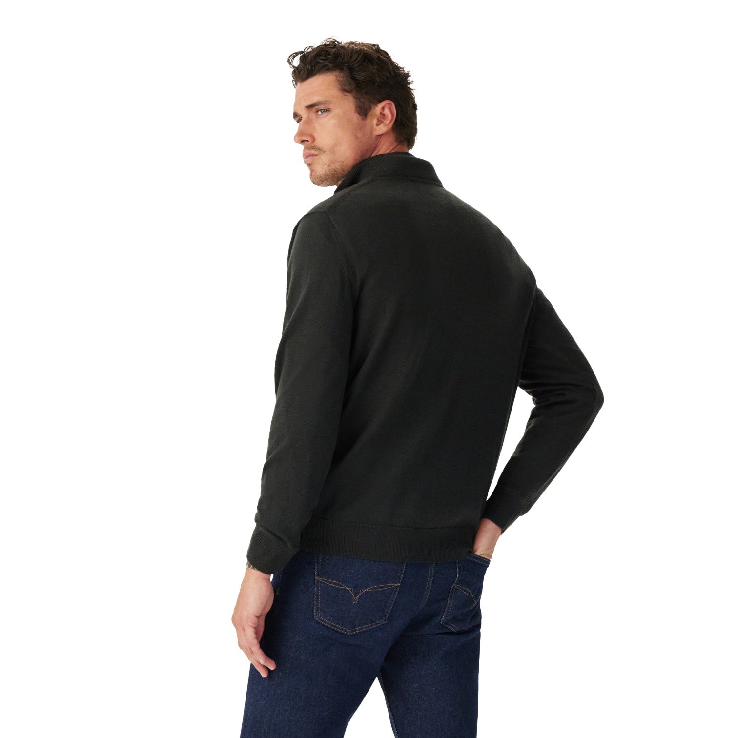 A man wearing a black long-sleeve quarter-zip pullover sweater, shown from a three-quarters back view, paired with dark blue jeans against a solid white background.