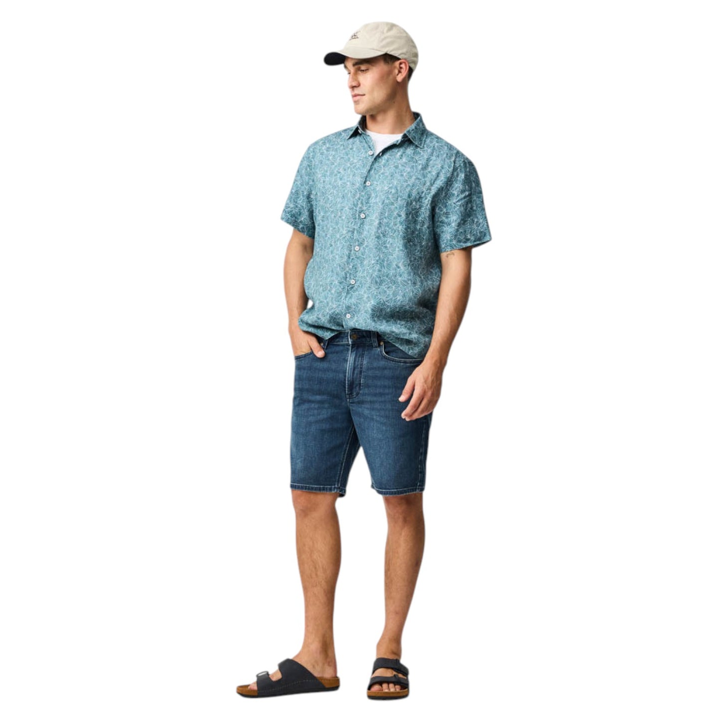 Man wearing a blue patterned shirt and denim shorts on a white background