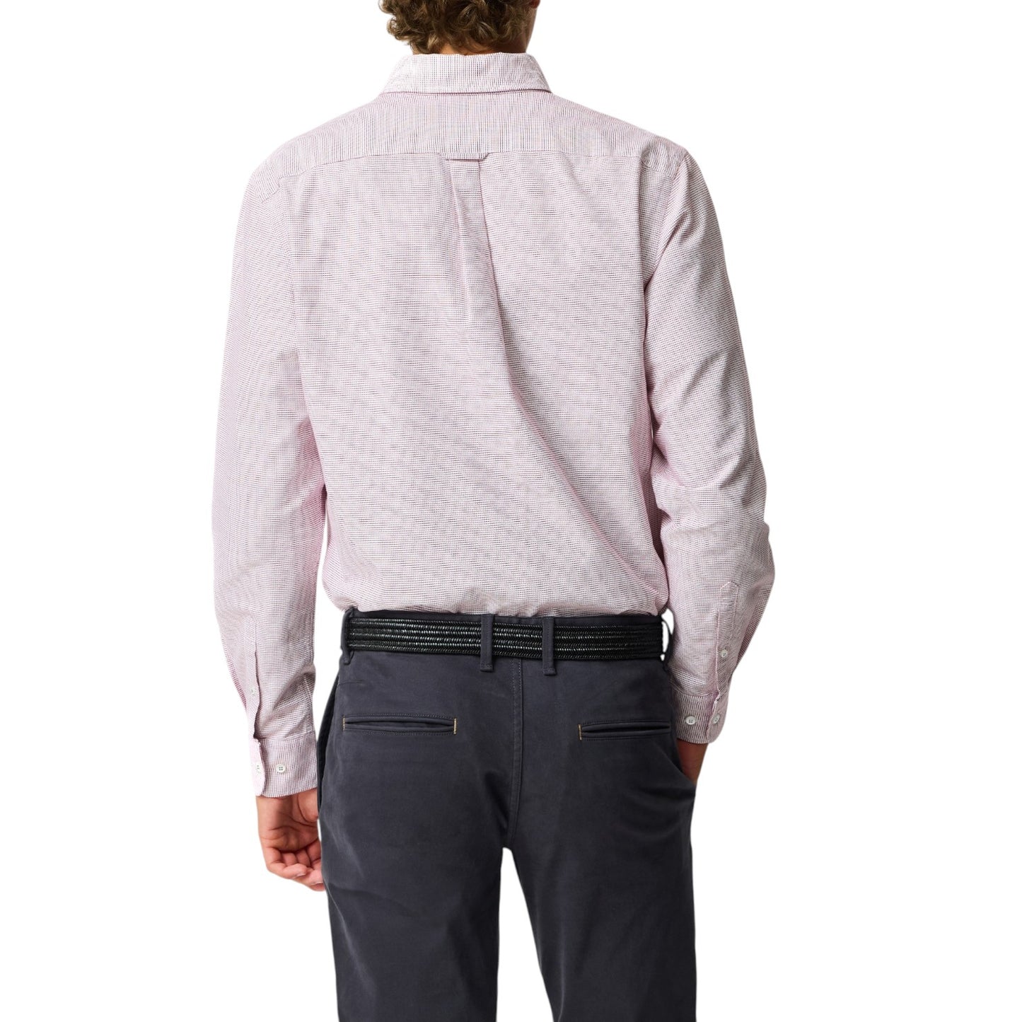 Person wearing a light pink patterned shirt and dark gray pants on a white background