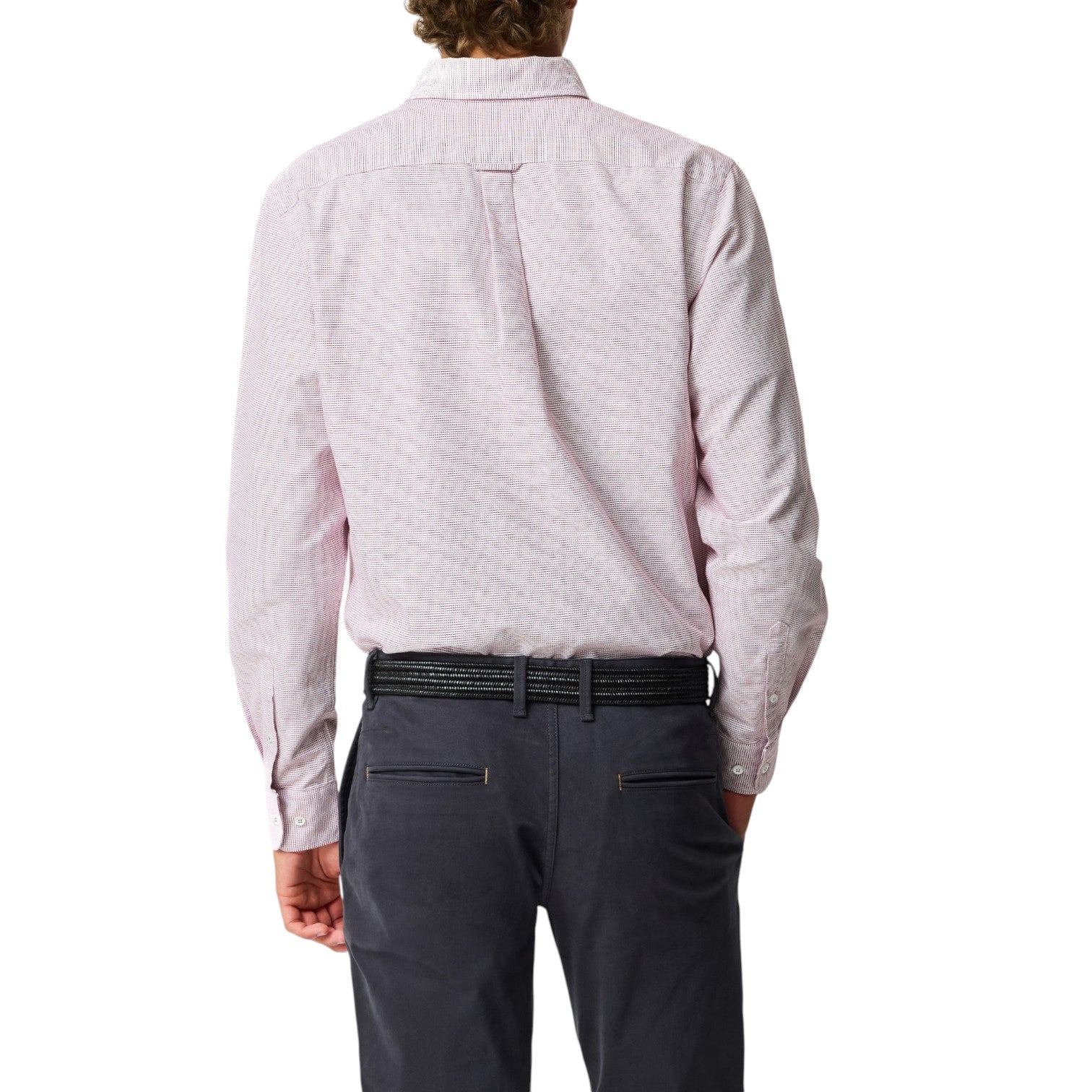 Person wearing a light pink patterned shirt and dark gray pants on a white background