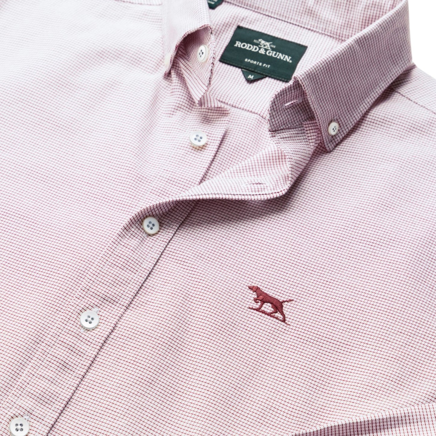 Close-up of a pink checkered shirt with a brand label on a white background